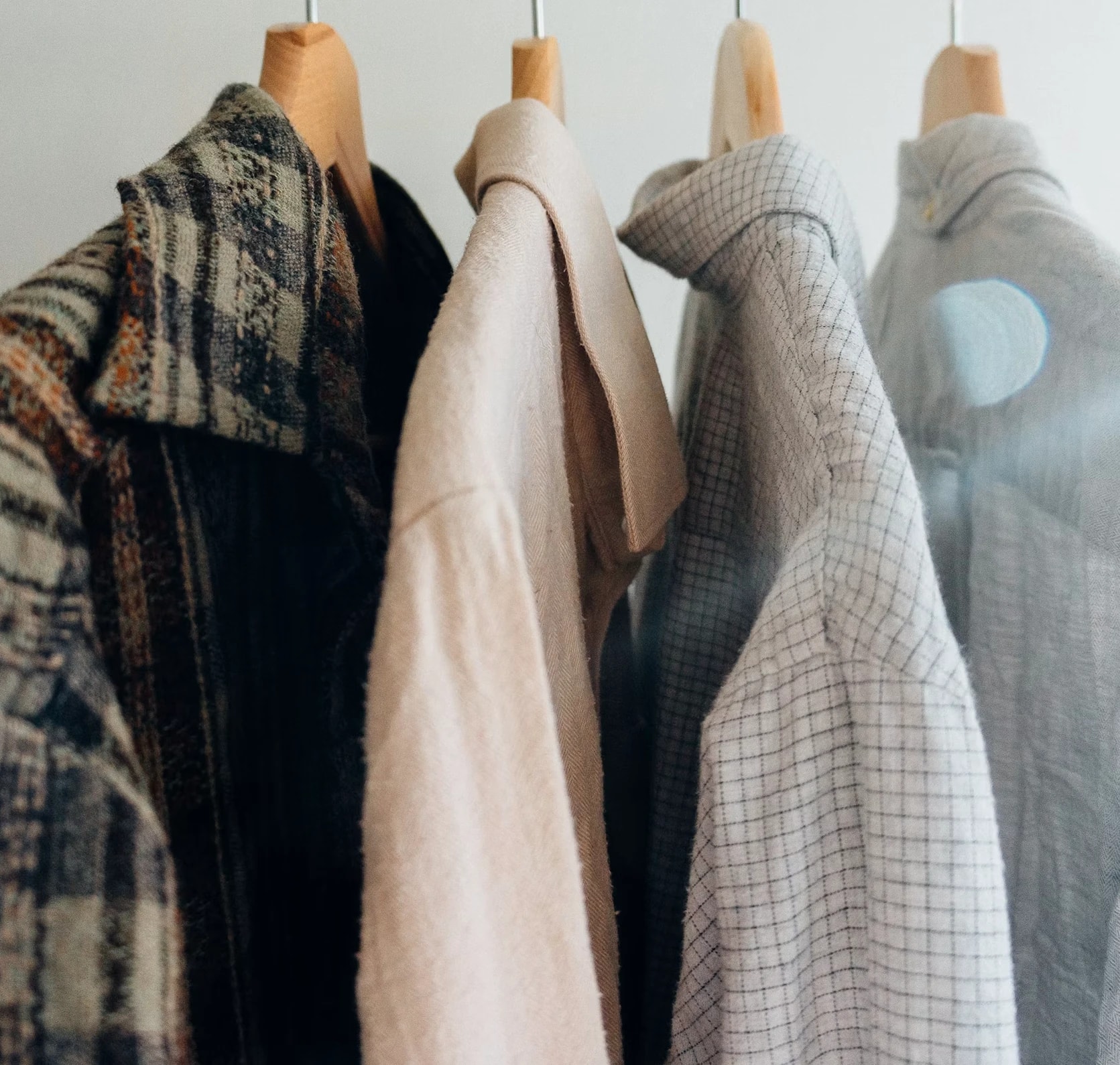 Plaid, cream and checked shirts hanging on wooden hangers