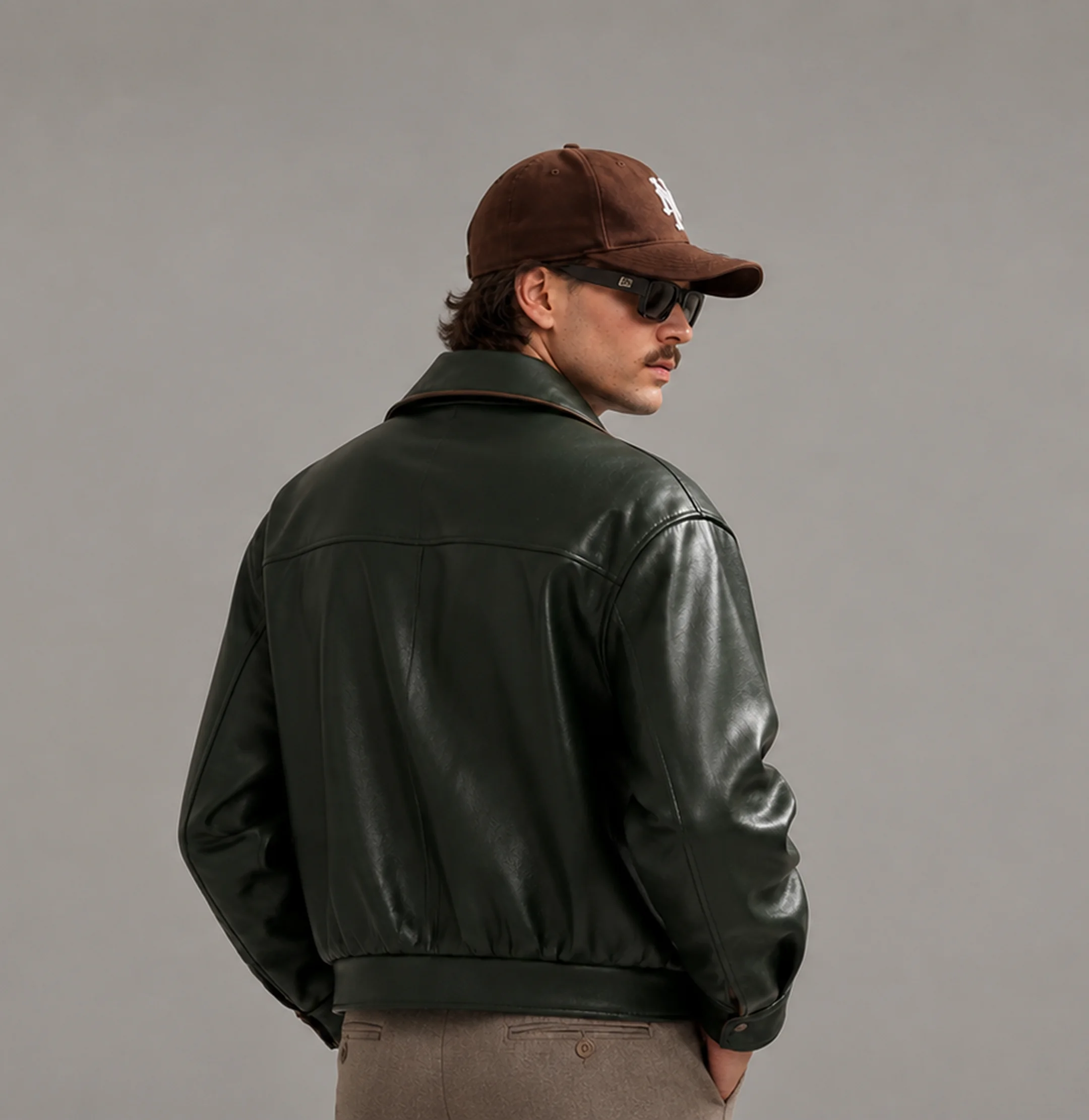 Man in a dark green leather jacket and cap, back view